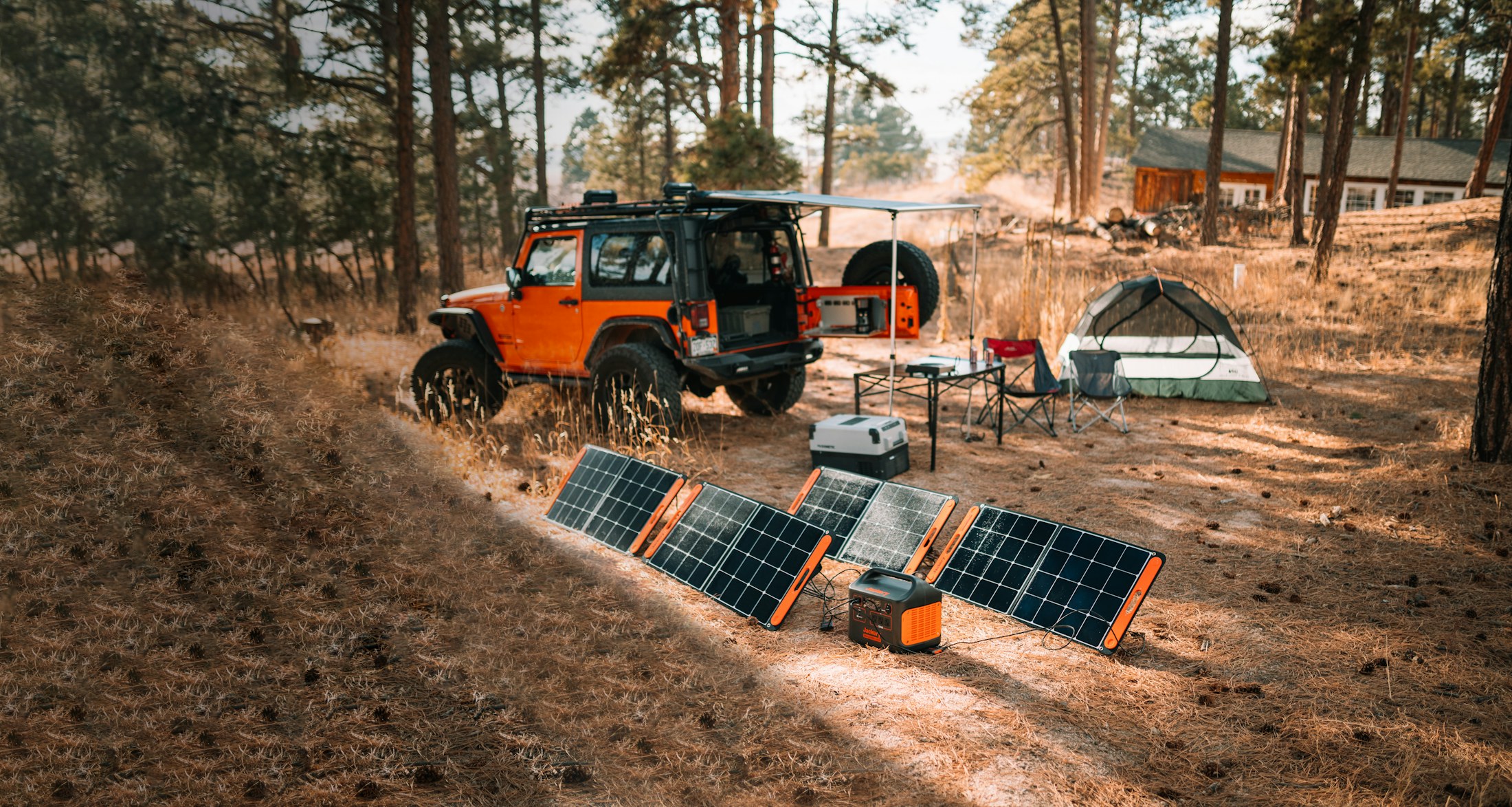 Portable solar panels and a battery at a forest campsite; illustrative photograph